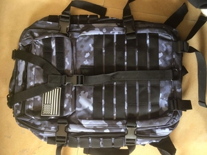 Macro detail of urban camo tactical backpack showing MOLLE webbing and US flag patch