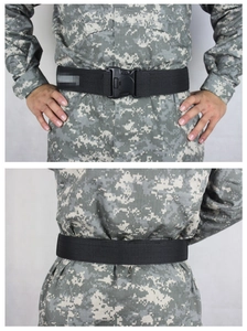 Detail of a tactical black nylon web belt with heavy-duty quick release buckle on camo pants