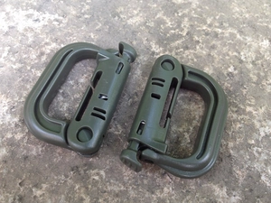 Army green tactical D-ring carabiner with spring gate on rugged stone background