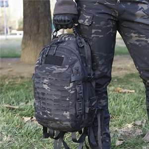 Tactical camouflage backpack with laser-cut Molle system held by a model in outdoor setting