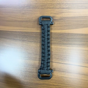 Outdoor paracord water bottle handle with double buckles on a wooden background