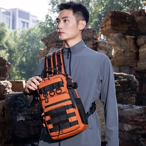 Detail of orange tactical chest bag featuring MOLLE webbing and elastic cords for hiking