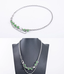 Détail du collier en chaîne argentée avec perles vertes sur un buste de bijoux