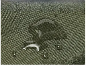 Close-up of waterproof army green tactical backpack fabric showing water droplets on nylon