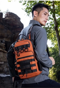 Detail of orange tactical backpack with MOLLE system and D-rings in outdoor setting