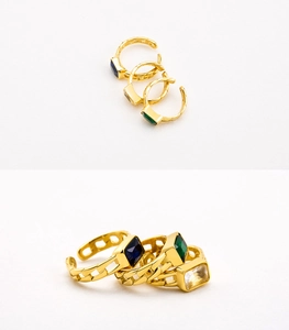 Vista detallada de tres anillos de cadena cubana dorados con cristales verdes, azules y claros