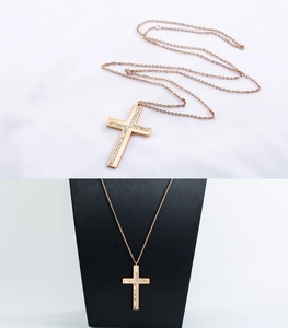 Detalle del collar de cruz de acero inoxidable oro rosa con pavé de cristales en busto negro