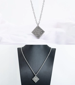 Macro detail of silver stainless steel square pendant with engraved character on silk