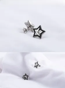 Macro detail of retro star stud earrings with silver texture and black enamel patterns