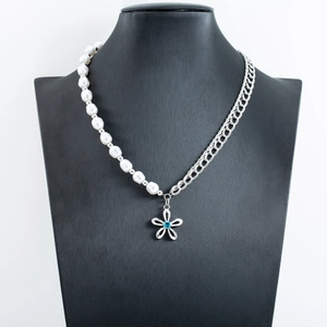 Irregular pearl and silver chain necklace featuring a floral pendant with blue gemstone