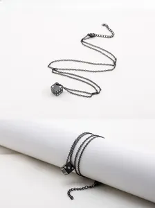 Détail du collier pendentif dé noir avec points blancs et chaîne réglable en acier
