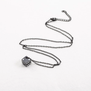 Collier unisexe avec pendentif dé carré en acier titane noir sur fond texturé blanc