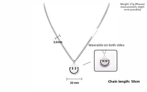 Dettaglio del ciondolo smiley a doppia faccia con simboli di dollaro e lettera su catena