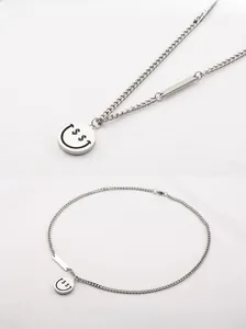Dettaglio della collana in acciaio argento con ciondolo smiley dollaro e barra di metallo