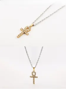 Macro detail of gold Ankh cross pendant with pavé crystals on silver O-chain necklace
