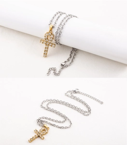 Detailed close-up of a gold Ankh cross pendant with crystals on a silver chain link