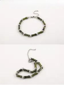 Macro detail of men's beaded bracelet featuring dark green bamboo-shaped jade and steel beads