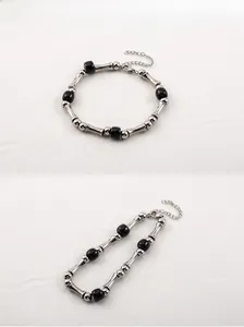 Detailed view of bamboo-style steel links and black beads on adjustable bracelet