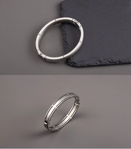Macro shot of silver titanium steel oval bracelet with grooved texture and rivet details