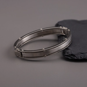 Gunmetal titanium steel bracelet featuring brushed texture and rivet details on dark stone