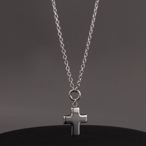 Polished silver hollow cross pendant necklace with classic O-chain on a dark display