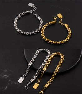 Dettaglio di bracciali a maglie quadrate in oro e argento con chiusura a moschettone su pietra