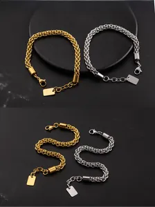 Macro detail of gold and silver woven stainless steel chain bracelets on black stone background