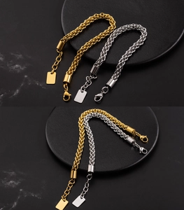Detail of chunky gold and silver braided lantern chain bracelets with lobster clasp and tag