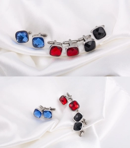 Macro shot of square crystal cufflinks in blue, red, and black on white silk background