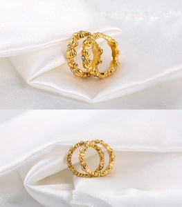 Detailed close-up of two gold-plated bow rings with small white zircon settings on silk