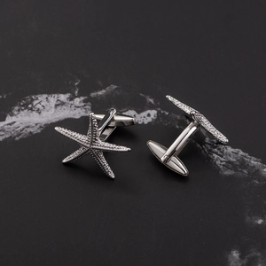 Polished silver starfish cufflinks for business suits on black marble background