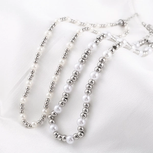 Elegant stainless steel bead and white pearl necklace on a white silk background