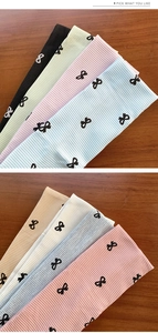 Détail de bandeaux en maille côtelée avec motifs de nœuds noirs en couleurs macaron