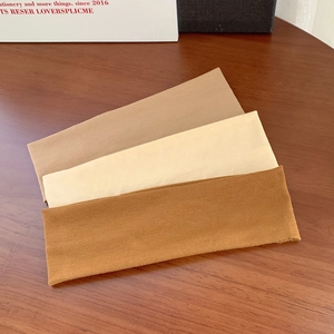 Three-pack elastic sports headbands in brown, cream, and tan on a wooden surface
