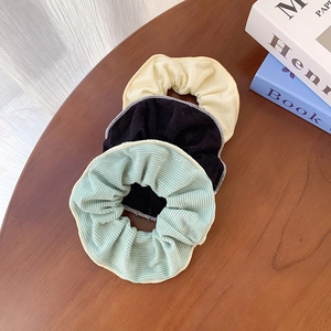 Macaron color knit hair scrunchies in yellow, black and green on wooden desk