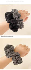 Detailed texture of black rhinestone scrunchie and silver grey metallic hair tie on wrist