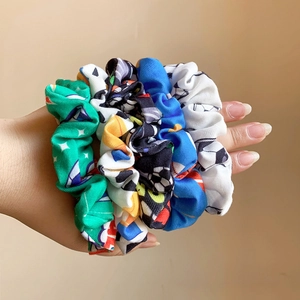 Set of stylish soccer pattern scrunchies in green and blue worn on the wrist