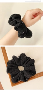 Detail view of black high-elastic scrunchie with sparkling rhinestones on fabric