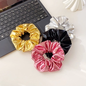 Set of four shiny metallic scrunchies in gold silver pink and black on white desk
