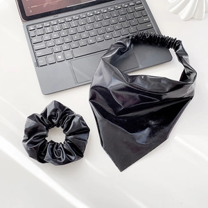 Detail of black faux leather hair scrunchie and triangular headband set in a modern setup
