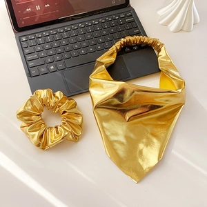 Flat lay of metallic gold hair accessories set with headband and elastic scrunchie