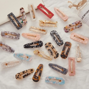 Chic acetate hair clips set with marble patterns and gold foil on white fabric background