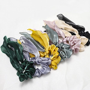 Flat lay of satin ribbon scrunchies in 7 colors like emerald green and lilac