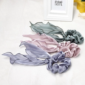 Detailed close-up of glossy satin and sheer organza hair scrunchies in soft pastel tones