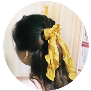 Golden satin bow scrunchie with long streamers shown on dark long hair in a pony tail