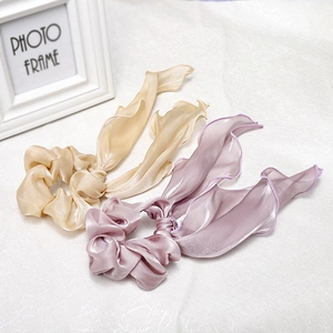 Macro shot of satin ribbon scrunchies showing glossy fabric texture and soft drape