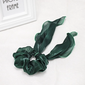 Detailed texture of dark green satin scrunchie with elegant long tails and glossy finish
