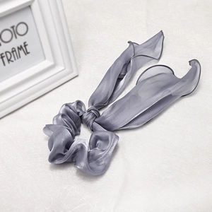 Close-up of elegant grey satin scrunchie with long ribbon bow and soft silky texture