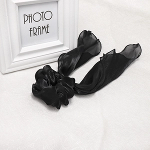 Detail of black satin hair scrunchie with long ribbon bow and delicate edge stitching