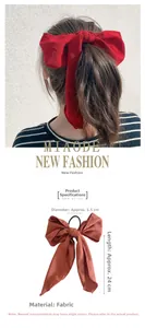Detail view of a red fabric bow hair tie with ribbons showing 24cm length and model look